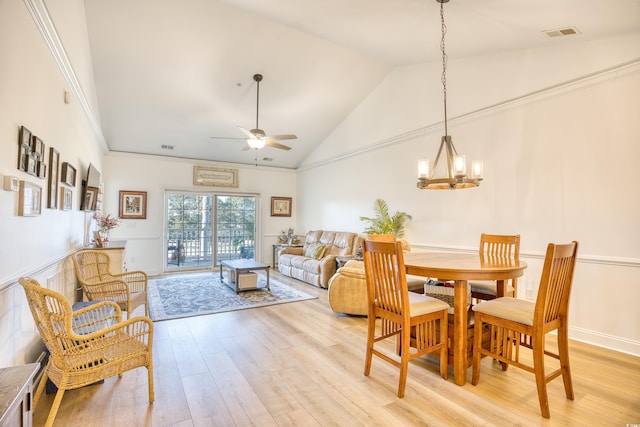 dining room with lofted ceiling, ceiling fan with notable chandelier, and light hardwood / wood-style flooring