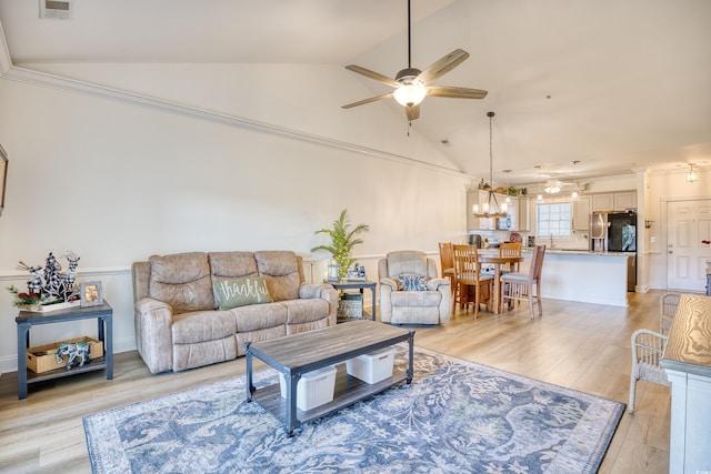 living room featuring ceiling fan with notable chandelier, lofted ceiling, and light wood-type flooring