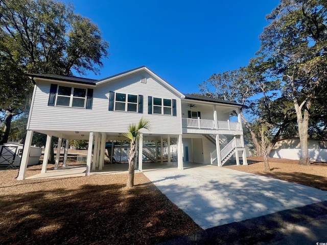 back of property with a carport, stairs, a ceiling fan, and concrete driveway