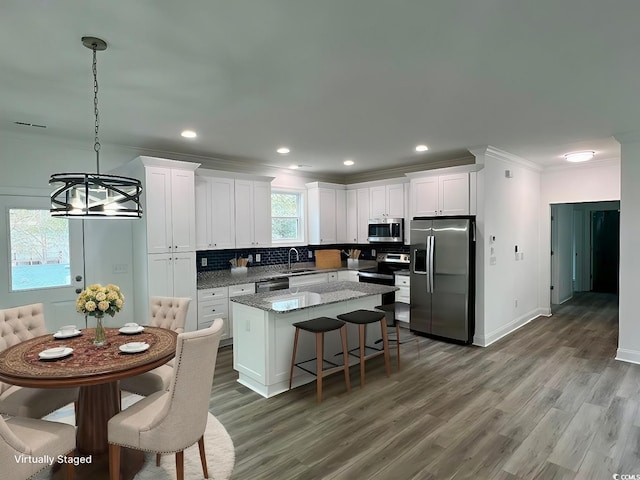 kitchen with decorative backsplash, appliances with stainless steel finishes, a center island, crown molding, and a sink