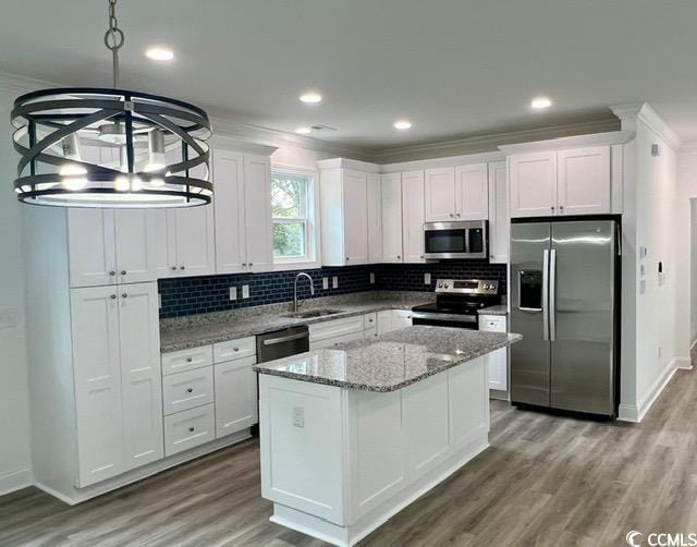 kitchen with a sink, white cabinetry, ornamental molding, appliances with stainless steel finishes, and backsplash