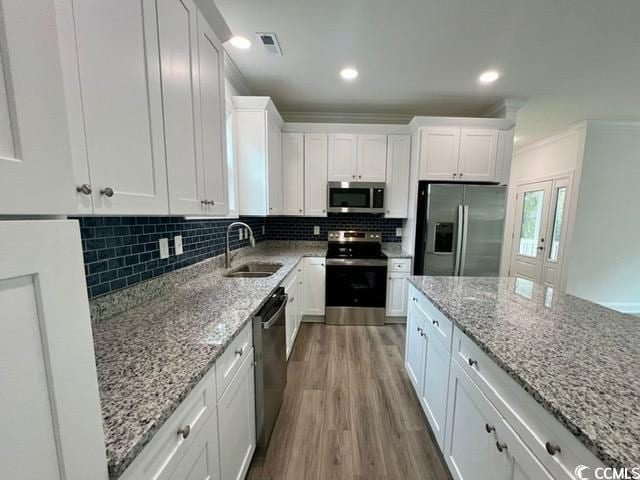 kitchen with tasteful backsplash, sink, light stone countertops, stainless steel appliances, and white cabinets