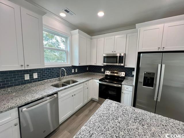 kitchen featuring stainless steel appliances, white cabinetry, and sink