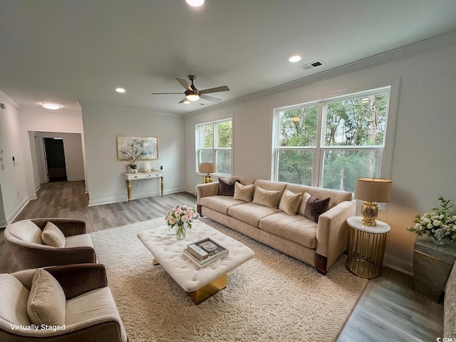 living area featuring recessed lighting, wood finished floors, visible vents, baseboards, and crown molding