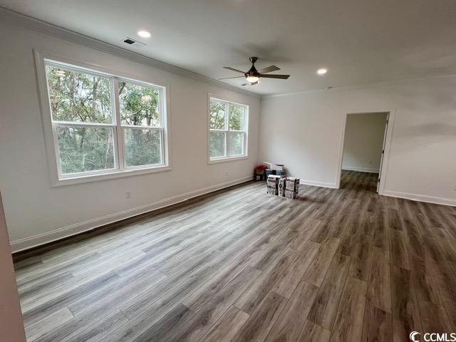 empty room featuring ceiling fan, ornamental molding, and wood-type flooring