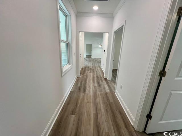 hall featuring ornamental molding, dark wood finished floors, visible vents, and baseboards