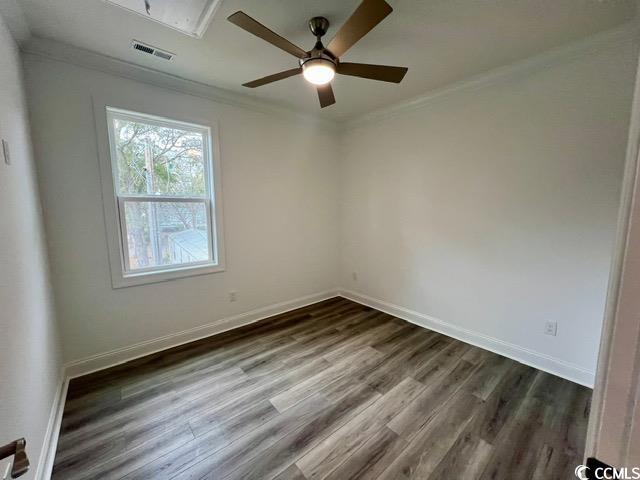 unfurnished room featuring baseboards, dark wood-style flooring, attic access, and crown molding