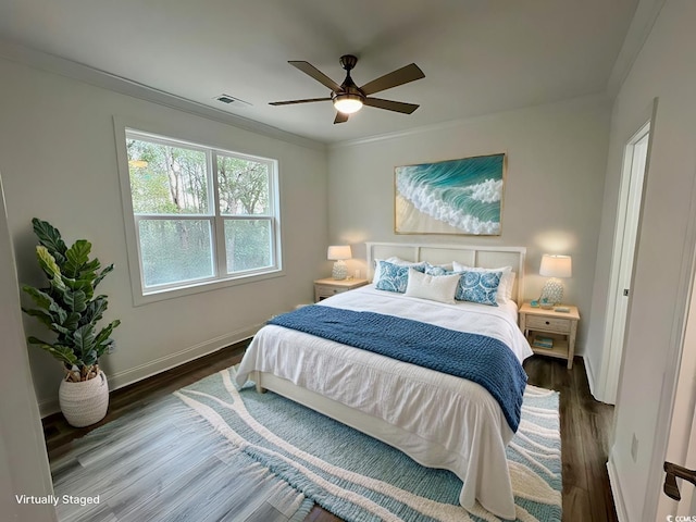 bedroom with ornamental molding, wood finished floors, visible vents, and baseboards