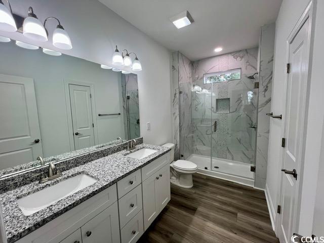 bathroom featuring toilet, vanity, a shower with door, and hardwood / wood-style floors