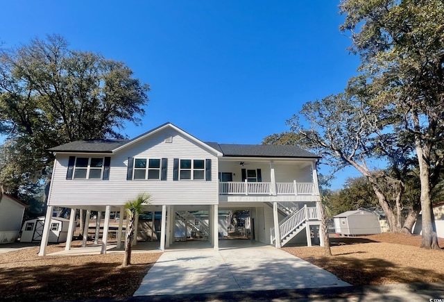 view of front of property featuring a ceiling fan, covered porch, stairs, an outdoor structure, and a carport