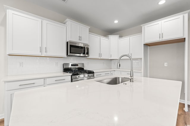 112 Lakota Loop, Longs, SC 29568 - kitchen with appliances with stainless steel finishes, a sink, light wood-style floors, white cabinets, and a kitchen island with sink