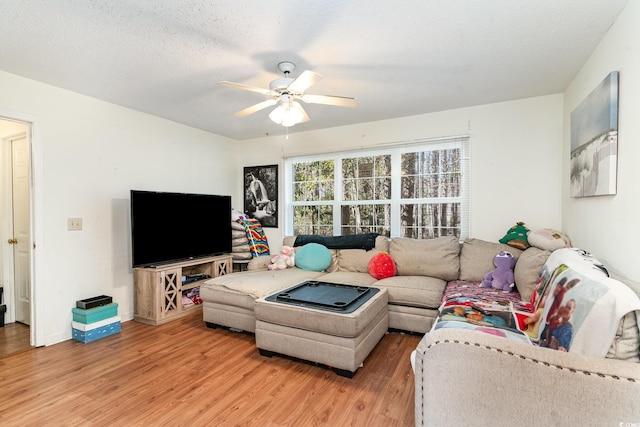 living room featuring a textured ceiling, ceiling fan, and light hardwood / wood-style flooring