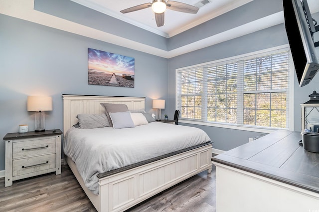 bedroom featuring ceiling fan, dark hardwood / wood-style floors, ornamental molding, and a raised ceiling