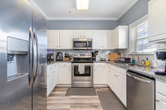 kitchen featuring light stone countertops, white cabinets, appliances with stainless steel finishes, light hardwood / wood-style floors, and sink