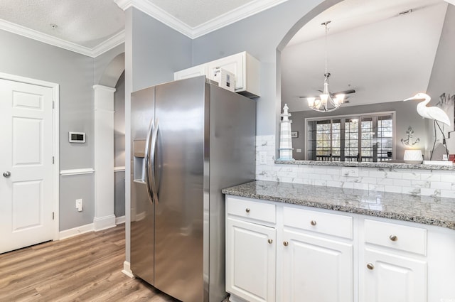 kitchen with decorative light fixtures, white cabinets, stone countertops, and stainless steel fridge