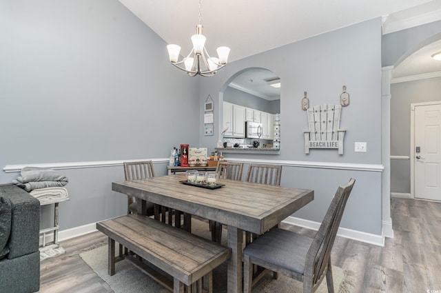 dining area with an inviting chandelier, ornamental molding, and light hardwood / wood-style floors