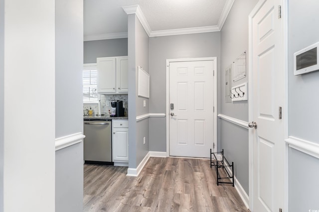 interior space featuring light wood-type flooring, crown molding, and a textured ceiling