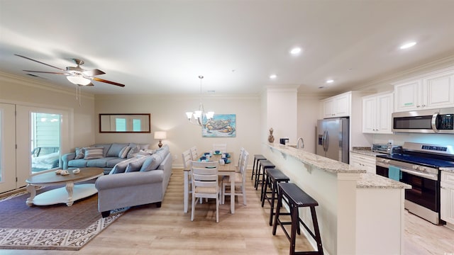 kitchen featuring decorative light fixtures, white cabinetry, a kitchen bar, stainless steel appliances, and light stone countertops