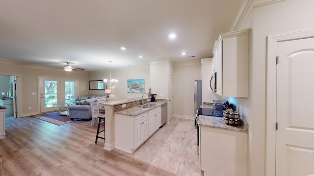 kitchen with sink, white cabinets, a kitchen bar, light stone counters, and stainless steel appliances