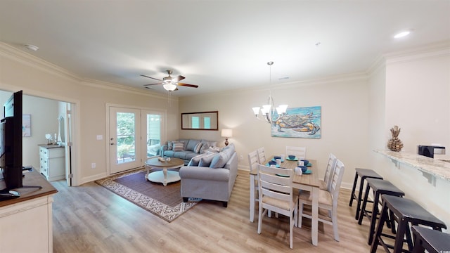 living room featuring ceiling fan with notable chandelier, ornamental molding, and light wood-type flooring