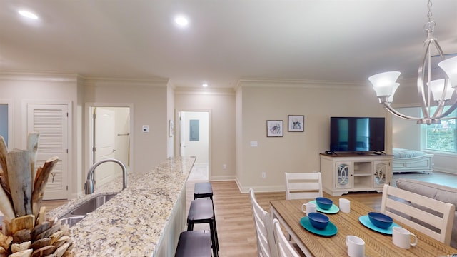 living room with sink, ornamental molding, light hardwood / wood-style floors, and a chandelier