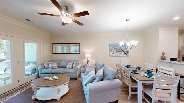 living room with ceiling fan with notable chandelier, wood-type flooring, and ornamental molding