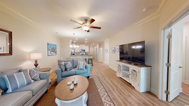 living room with ceiling fan with notable chandelier, ornamental molding, and light hardwood / wood-style floors