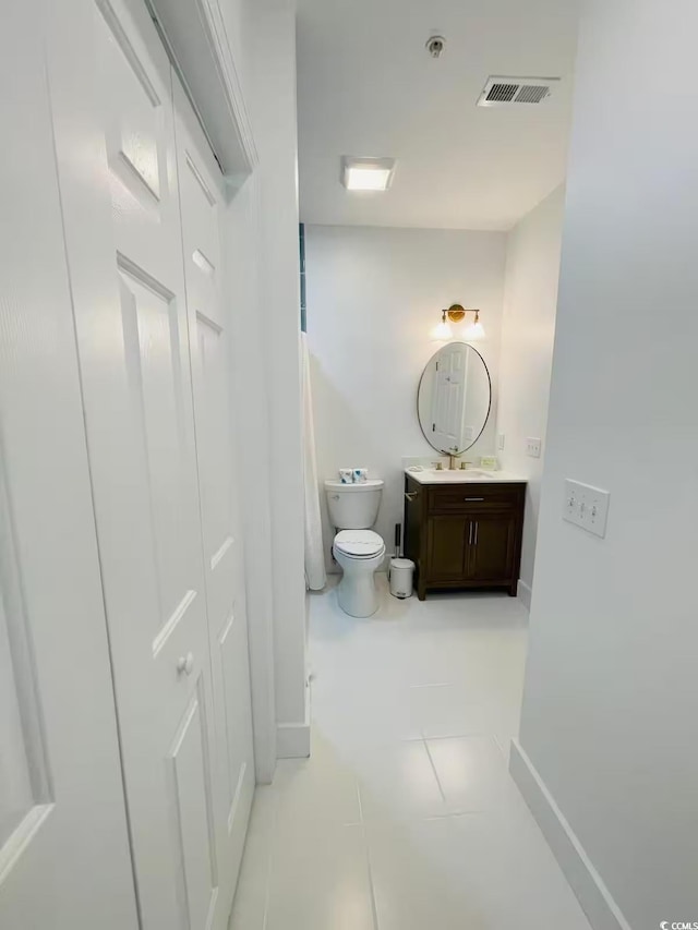 bathroom with toilet, vanity, and tile patterned flooring