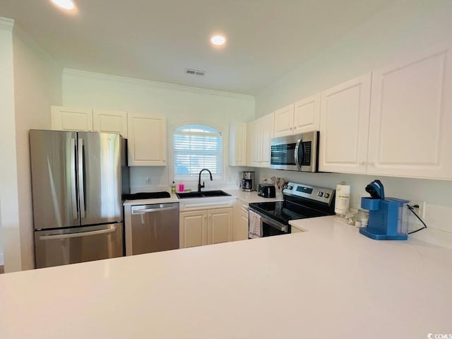 kitchen with appliances with stainless steel finishes, ornamental molding, white cabinetry, and sink