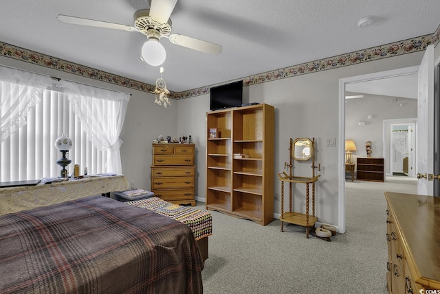 bedroom featuring ceiling fan, light colored carpet, and a textured ceiling