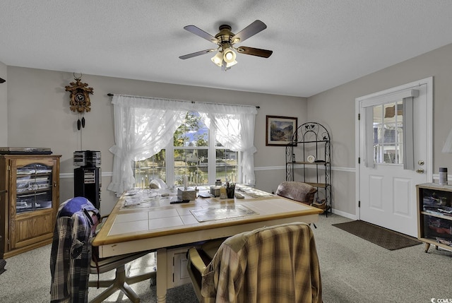 carpeted dining area featuring ceiling fan and a textured ceiling