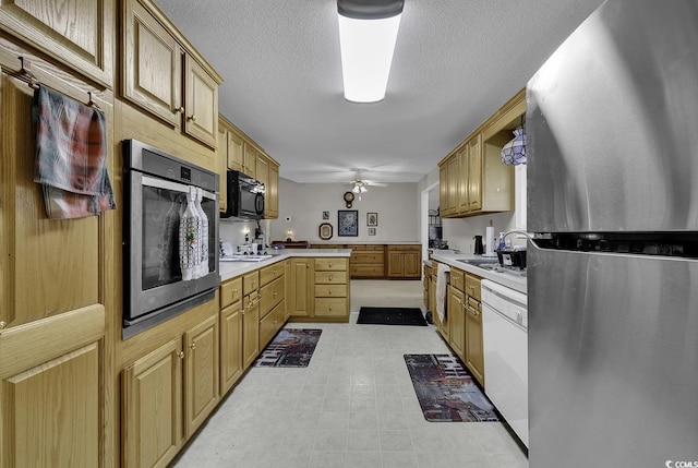 kitchen with ceiling fan, sink, stainless steel appliances, and a textured ceiling