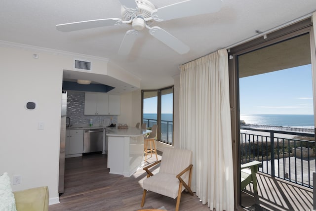 interior space featuring dark hardwood / wood-style floors, tasteful backsplash, stainless steel dishwasher, ceiling fan, and a water view