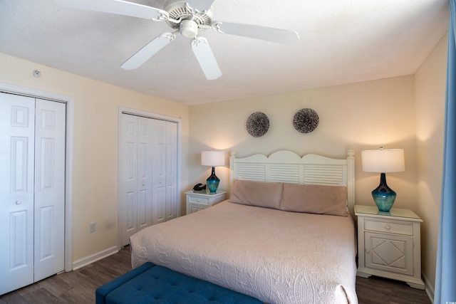 bedroom with dark wood-type flooring, two closets, and ceiling fan