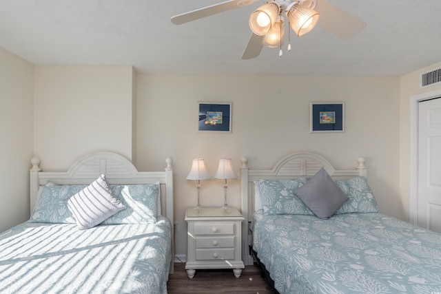 bedroom with ceiling fan, dark hardwood / wood-style floors, and a textured ceiling