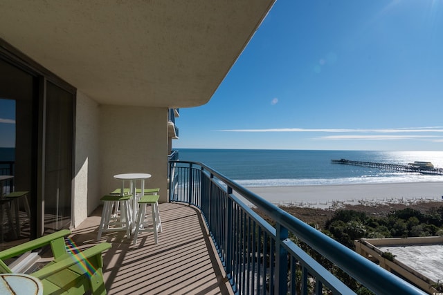 balcony featuring a view of the beach and a water view