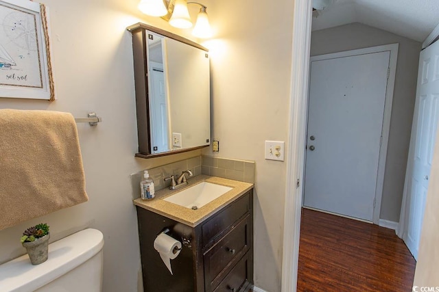 bathroom with vanity, wood-type flooring, vaulted ceiling, and toilet