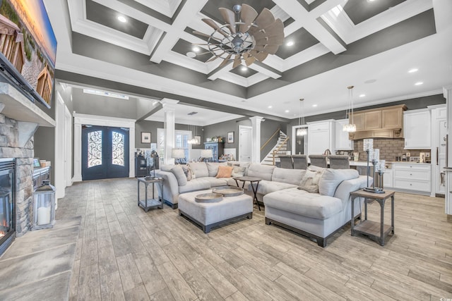 living room with coffered ceiling, decorative columns, ornamental molding, ceiling fan, and light hardwood / wood-style floors