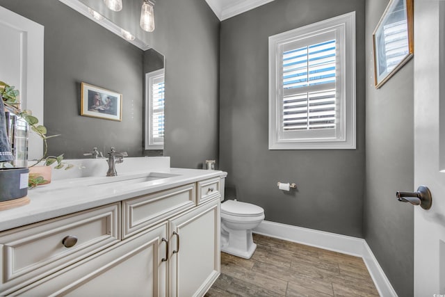 bathroom with crown molding, a healthy amount of sunlight, toilet, and vanity