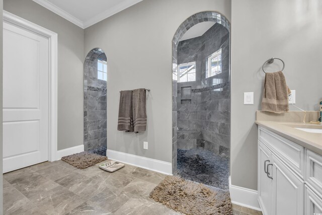 bathroom featuring crown molding, plenty of natural light, a tile shower, and vanity