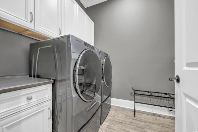 laundry area with cabinets, crown molding, separate washer and dryer, and light hardwood / wood-style flooring