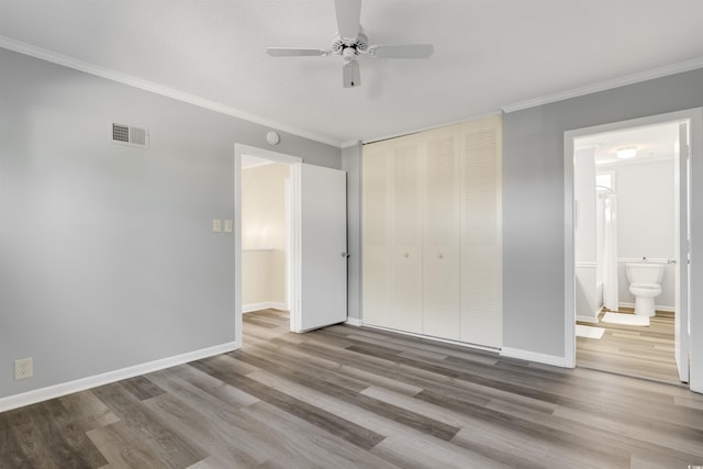 unfurnished bedroom featuring ensuite bathroom, ceiling fan, hardwood / wood-style flooring, ornamental molding, and a closet