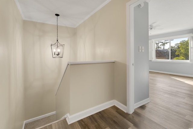 stairway with ornamental molding, ceiling fan with notable chandelier, and wood-type flooring