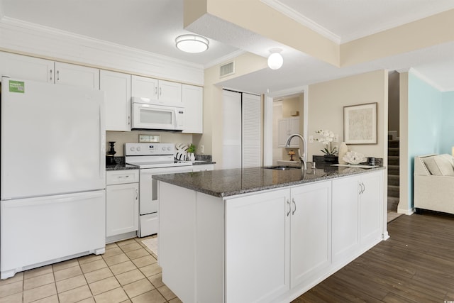 kitchen with an island with sink, white appliances, crown molding, white cabinets, and sink