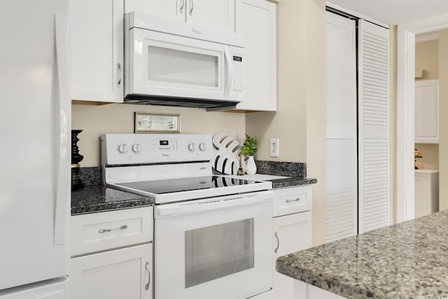 kitchen with white cabinets, dark stone counters, and white appliances