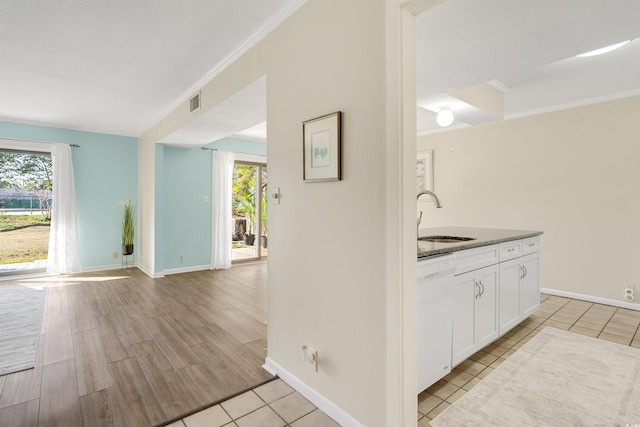 kitchen with plenty of natural light, sink, white dishwasher, and white cabinetry