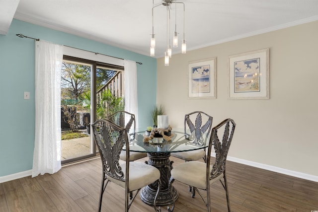 dining space with hardwood / wood-style flooring, crown molding, and an inviting chandelier