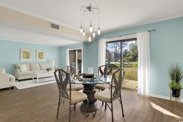 dining room featuring hardwood / wood-style floors, crown molding, and a notable chandelier