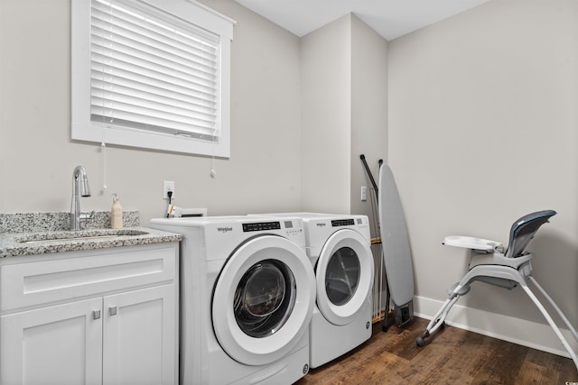 clothes washing area featuring washer and dryer, dark hardwood / wood-style flooring, sink, and cabinets