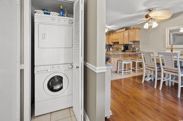 laundry room with ceiling fan, stacked washer / dryer, and light tile patterned floors